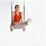 Young male gymnast performing routine on rings