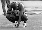 Male athlete crouching, head down, b&w