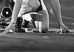 Male runner at starting block, low angle view, close-up, b&w