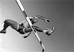 Male athlete jumping hurdle, low angle view, blurred motion, b&w