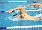 Male swimmers faisant freestyle en piscine, gros plan