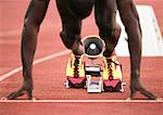 Male runner on starting block, low section, close-up