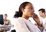 Businesspeople in office, woman using cell phone, side view
