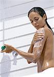 Femme prenant la douche en plein air, taille vers le haut, vue latérale