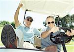 Two mature men in golf cart, smiling, close-up