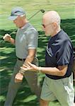 Two mature golfers walking on green