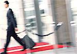 Businessman walking with luggage, side view, blurred