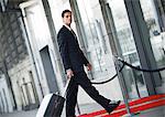 Businessman walking with luggage outside, side view