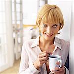 Teen girl leaning against wall, holding mug, portrait