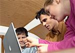 Father, son and daughter looking at laptop computer together.