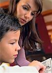 Mother looking at book with son, close up.