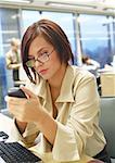 Businesswoman punching numbers on cell phone in office.