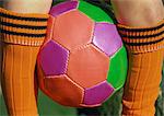 Colorful soccor ball between child's legs, close up