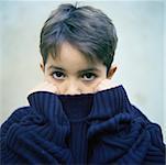 Boy holding sweater collar over mouth, portrait