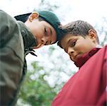 Two boys face to face looking at camera, low angle view