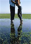 Jeune couple debout dans une flaque d'eau embrasse passionnément