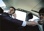 Homme d'affaires sur le téléphone cellulaire dans la banquette arrière de voiture, payer le chauffeur de taxi, vue d'angle faible