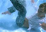 Fully clothed man at bottom of swimming pool, smiling