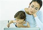 Woman with eyes closed holding little girl drawing with pen