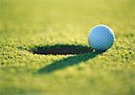 Golf ball at edge of hole, close-up