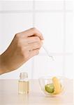 Woman's hand dropping oil into bowl with lemon zest