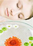 Woman's face and bowl of flowers floating in water