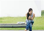 Young woman sitting on end of bench looking at cell phone