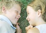 Boy and girl lying in grass, smiling