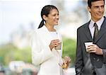 Businesswoman and man standing, having coffee outdoors