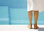 Femme portant debout peignoir de côté de la piscine, la vue arrière des jambes