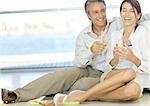 Adult couple sitting on floor, holding champagne flutes