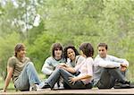 Group of young adult friends sitting around outside together