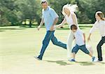 Family holding hands and running across grass