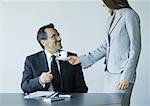 Woman handing mature businessman cup of coffee
