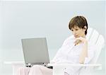 Woman sitting in deckchair using laptop