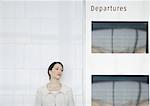Woman leaning against wall by departure board