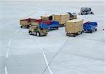 Chariots de bagages et oontainers sur la piste de l'aéroport