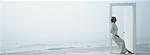 Woman leaning against doorframe on beach