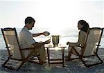 Newlyweds, husband serving wife champagne on beach