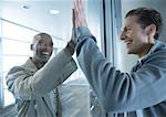 Two men putting palms together on either side of window