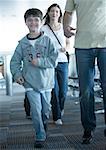 Boy walking through airport with parents, smiling