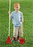 Boy standing with rake and shovel, portrait
