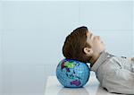 Boy resting head on globe