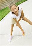 Girls drawing hopscotch squares on concrete