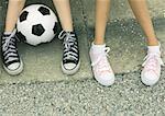 Deux enfants assis sur le trottoir, vue des pieds