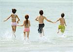 Enfants qui courent dans le surf à la plage