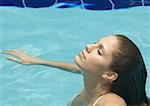 Femme debout dans la piscine avec la tête en arrière et les yeux fermés