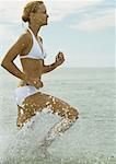 Woman running in surf, side view