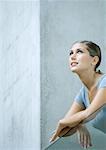 Woman leaning arms on balcony, looking up