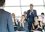 Executives in seminar, one man holding microphone, others clapping